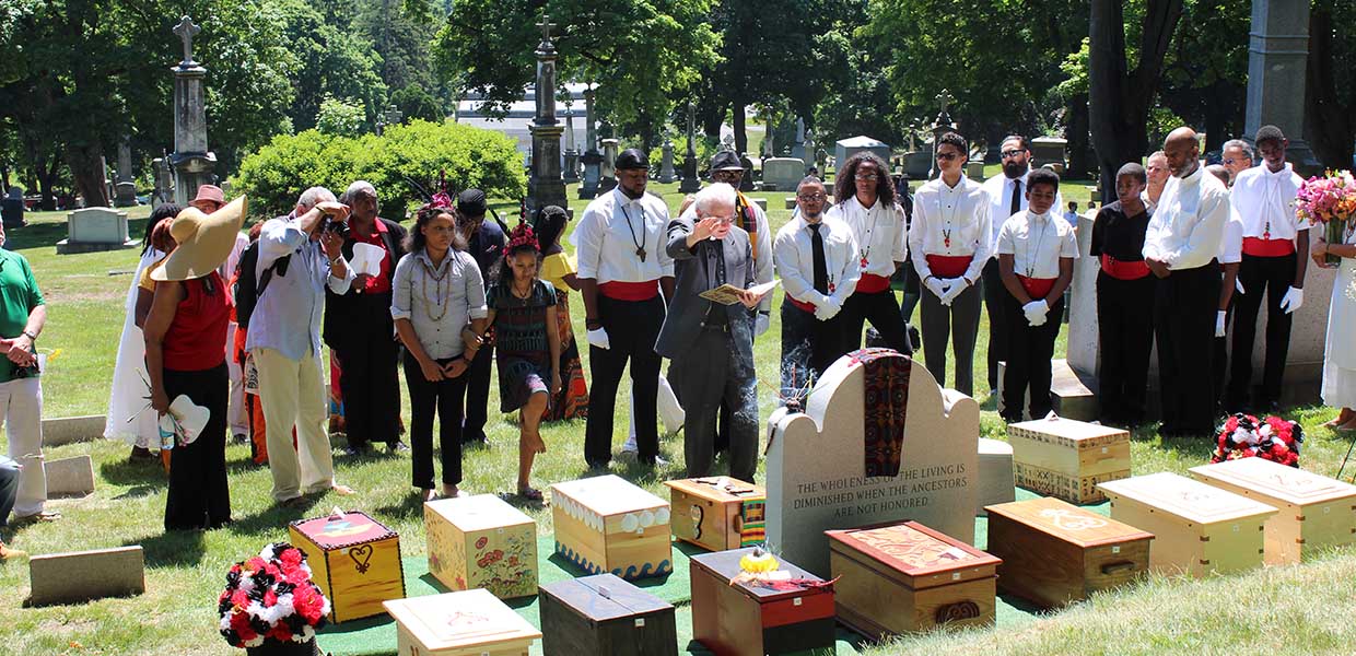 A blessing is offered over the remains of 18th Century slaves in St. Agnes Cemetery